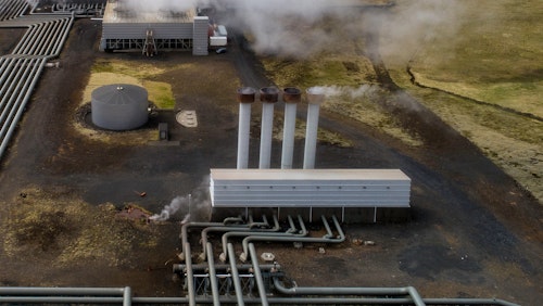 Photo depicts Hellisheidi geothermal powerplant shot from the air in early june, pipes and steam visible