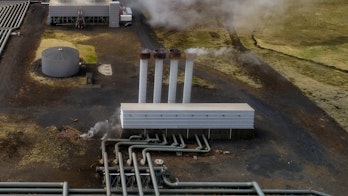 Photo depicts Hellisheidi geothermal powerplant shot from the air in early june, pipes and steam visible