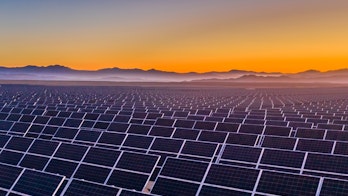 Photo depicts and aerial view of hundreds solar energy panels rows along the dry lands at Atacama Desert, Chile. Huge Photovoltaic PV Plant in the middle of the desert from an aerial drone point of view during sunset