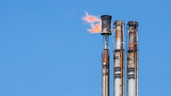 Photo depicts Burning oil flare on a blue sky