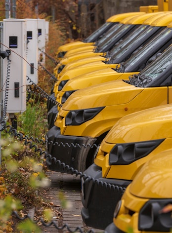 Photo shows a line of yellow electric cars plugged in to charging points