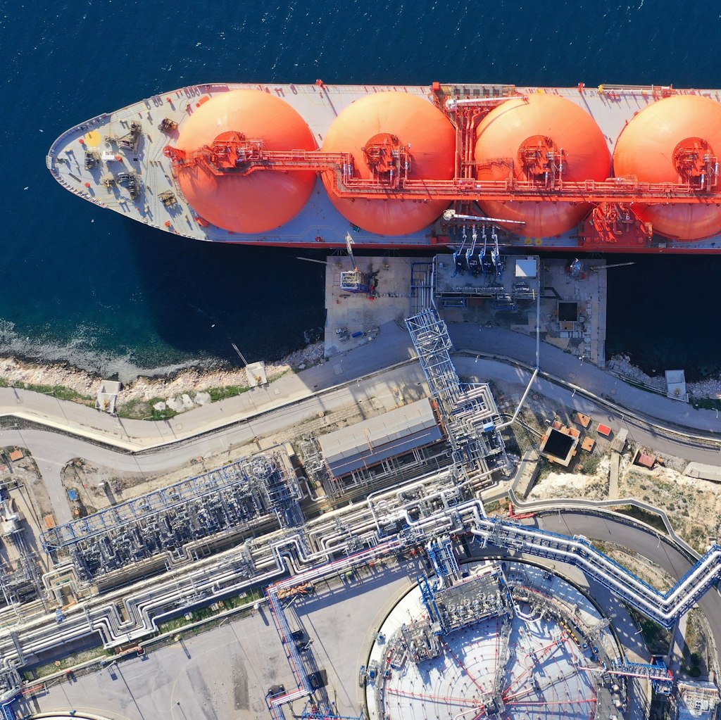Photo shows an aerial view of a LNG barge in water at the port of a gas facility